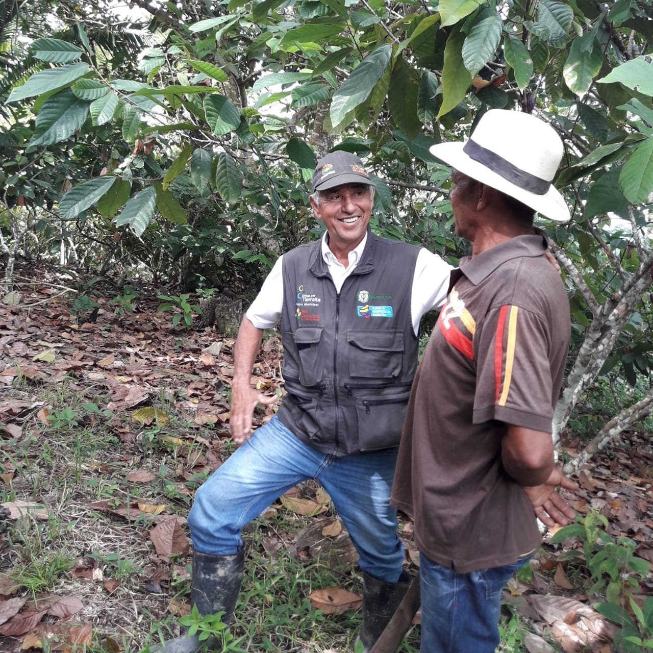 Un técnico agropecuario conversa con un campesino en un cultivo de cacao del Chocó